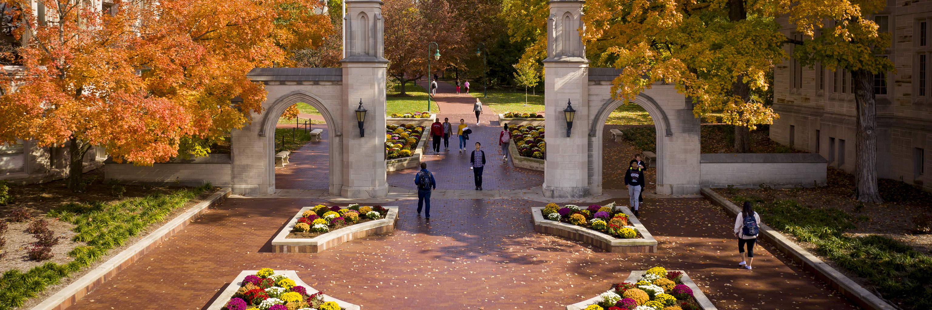 Students walk through the Indiana University Bloomington campus on a scenic fall day.