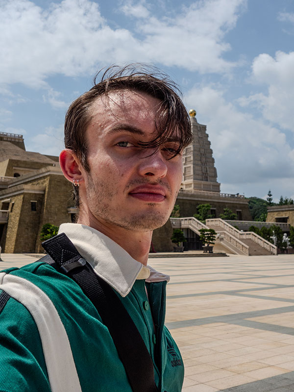 A photo of Baumgarten, who wears a green shirt and poses outside.