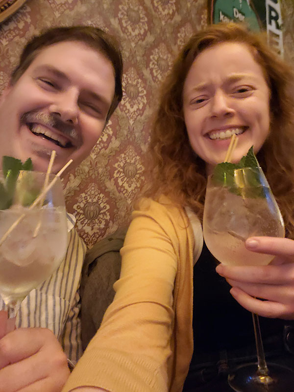 Two people holding drinks in a casual indoor setting.