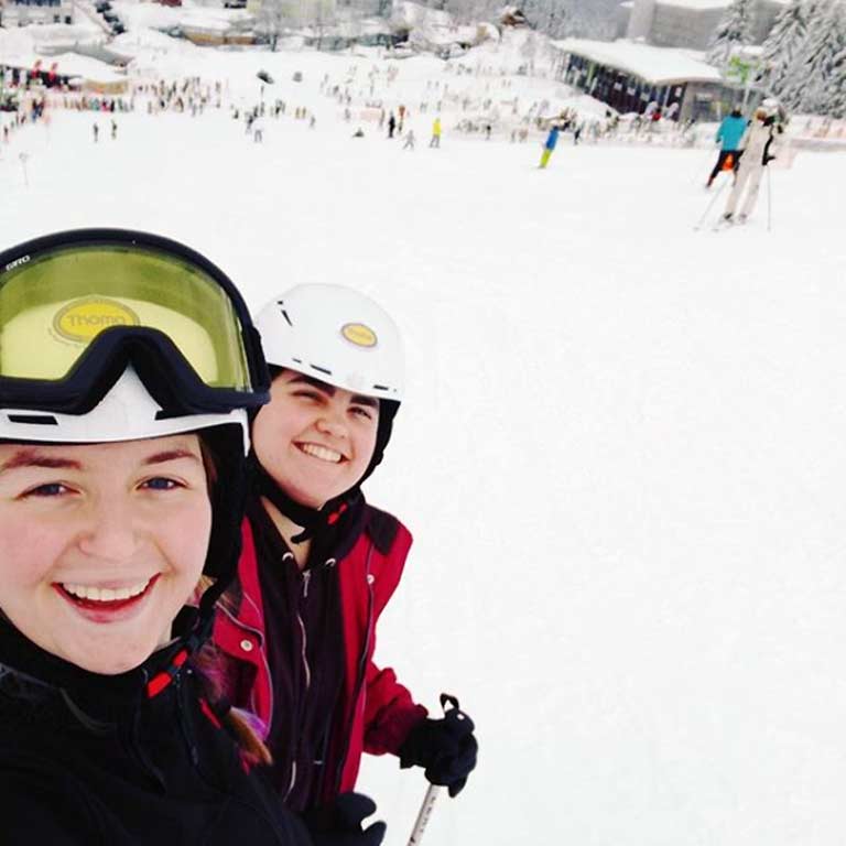 two students enjoying skiing at a slope